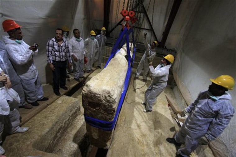 In this Thursday, June 23, 2011 file photo, an Egyptian and Japanese team of scientists use a pulley system to lift the first of 41 16-ton limestone slabs to reveal fragments of the ancient ship of King Khufu next to the Great Pyramid of Giza, Egypt. Archaeologists began a second-phase of restoration work on a 4,500-year-old wooden boat found next to the Great Pyramid of Giza, one of Egypt's main tourist attractions. (AP Photo/Khalil Hamra, File)